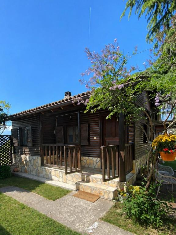Η ξύλινη βεράντα του Cozy Chalet από τον κήπο, με αναρριχώμενο φυτό πάνω στους στύλους.